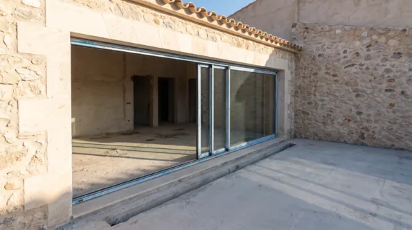 Large sliding glazed opening at a level threshold in a Mallorcan house with a drainage channel