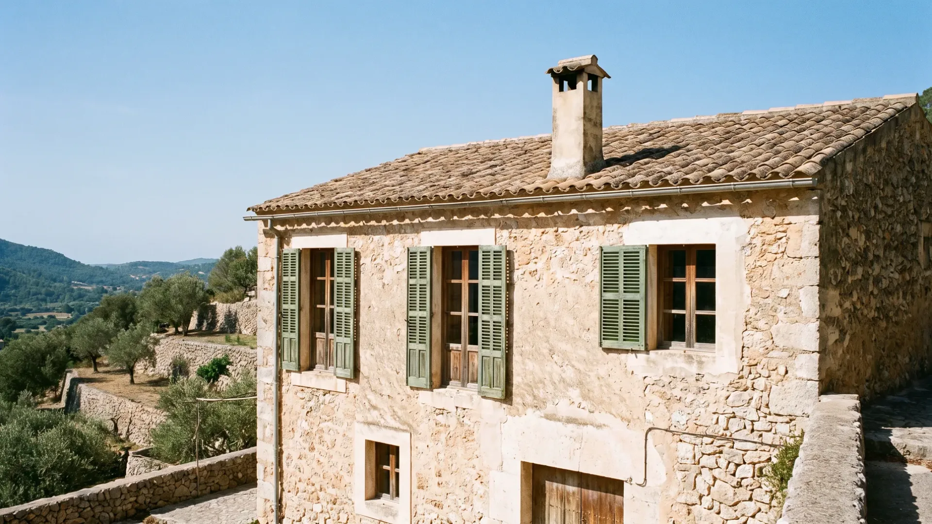 Casa mallorquina de piedra en lo alto de una ladera sobre el llano con muros gruesos y jambas profundas