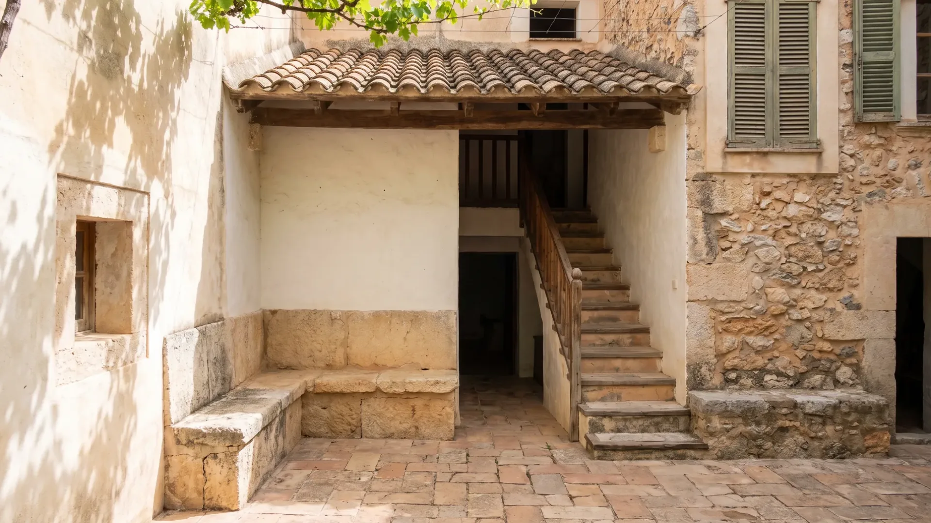 Shaded courtyard of a Mallorcan town house with lime-washed walls and terracotta paving underfoot