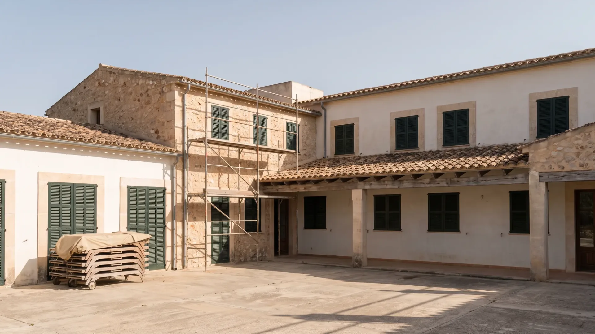 Shuttered Mallorcan hotel out of season with loungers stacked on an empty pool terrace