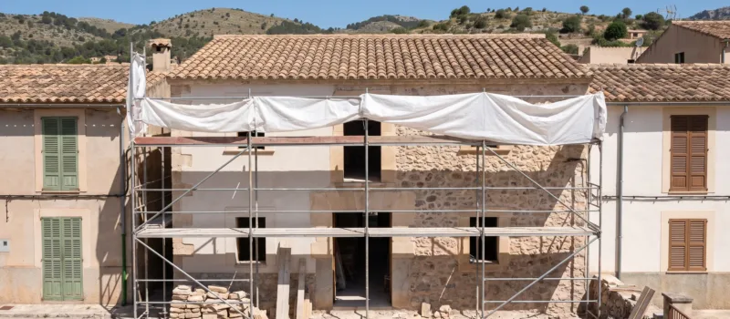 Casa mallorquina en reforma con los trabajos cubiertos con lonas y la obra cerrada por hoy