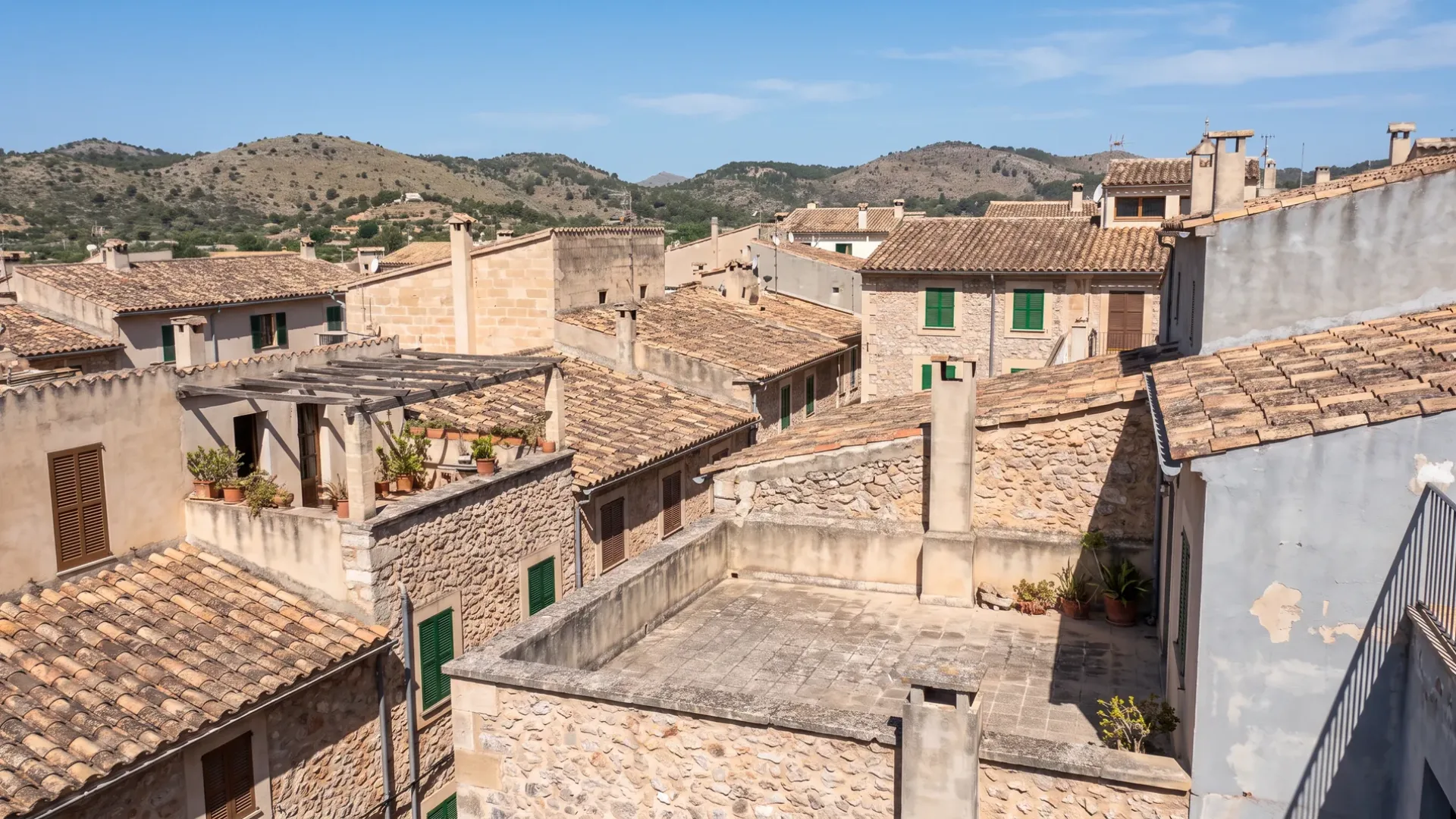 View across Mallorcan rooftops of terracotta tile, stone party walls and roof terraces