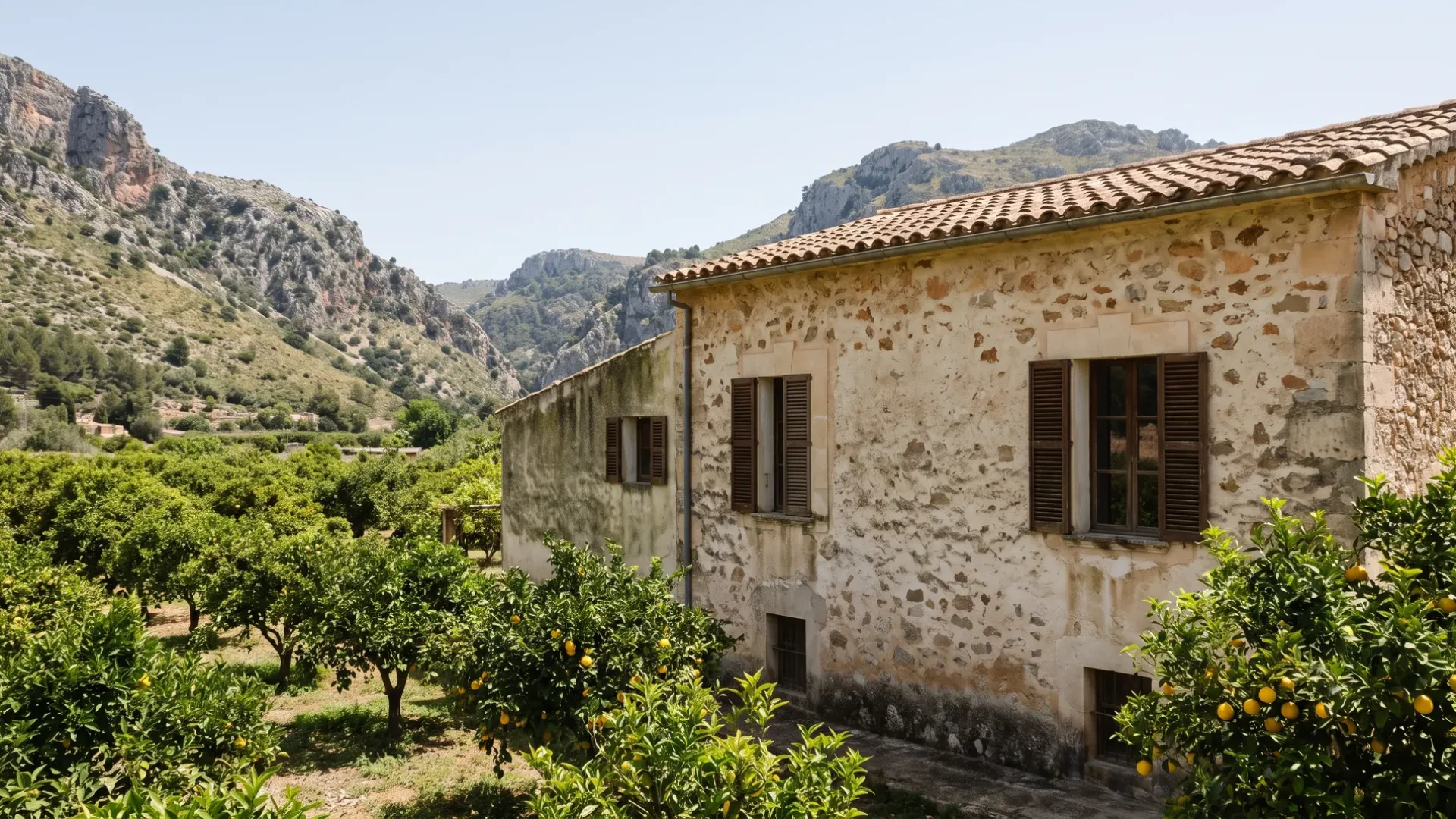 Stone finca in a green Mallorcan orchard valley with damp staining at the base of the render