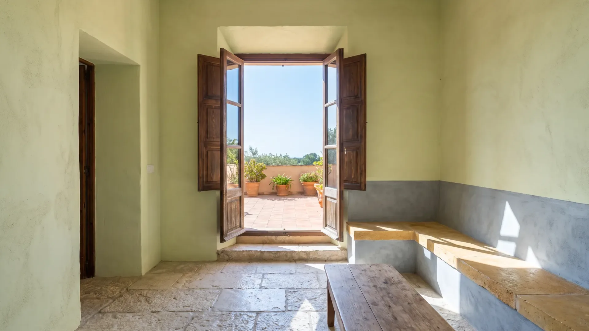 Finished Mallorcan villa interior with a stone floor, plastered walls and a shuttered opening