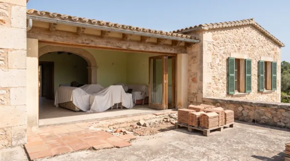 Closed Mallorcan villa with the furniture sheeted and a section of terrace tiling lifted outside
