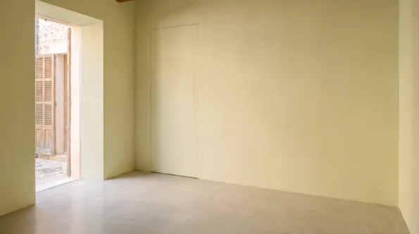 Minimalist Mallorcan room with one unbroken plane of matt plaster and a concealed door line